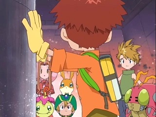 Koushirou stands before his friends, running his hands over the giant battery.