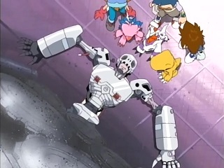 Taichi, Agumon (small yellow T-rex inspired Digimon), Piyomon (pink bird Digimon), Sora (girl with short, brown hair in a yellow shirt, blue trousers, and pink gloves), Gomamon (small, white seal/dog with purple markings and a red mohawk), and Jou (boy with short, blue hair, glasses, a pale yellow sweatervest over a white collared shirt, and brown shorts) stand over Andromon, an android Digimon, who has somehow gotten his waist stuck in a wall of gears.